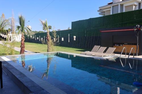 a swimming pool with two lounge chairs and a building at lamoza in Narlıdere