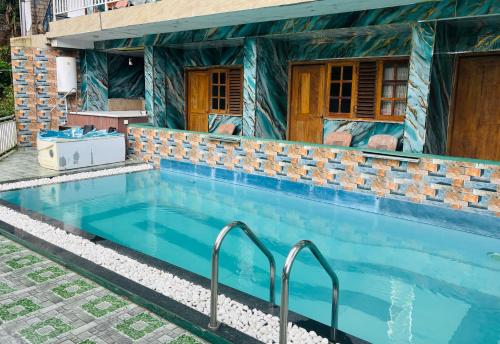 a swimming pool in front of a house at Grand adamspeak hotel & restaurant in Adams Peak