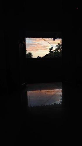 a window with a reflection of a sunset in the water at Gawade Niwas in Corgao