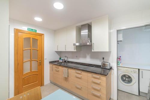 a kitchen with a sink and a washing machine at Acogedor apartamento ideal para familias in Barañáin