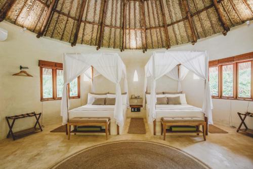 a bedroom with two beds and a thatched roof at ONE Santuario Natural in Palomino