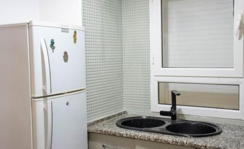 a kitchen with a sink and a white refrigerator at Appartement a Kantaoui in Port El Kantaoui