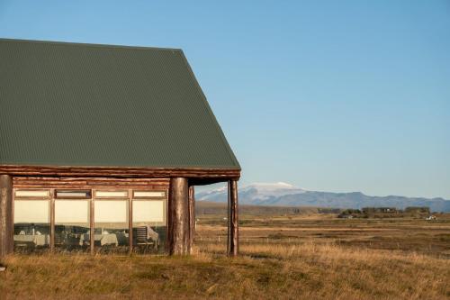 an old building in a field with mountains in the background at Hotel Rangá in Hella