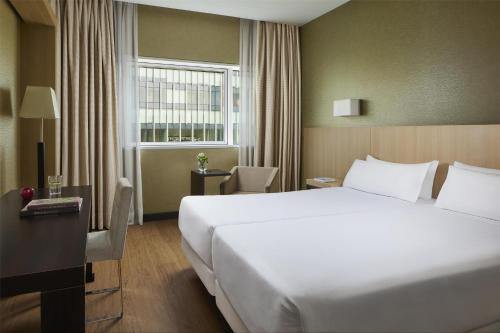 a hotel room with a large white bed and a window at NH Madrid Ribera del Manzanares in Madrid