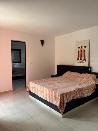 une chambre avec un lit et une télévision à écran plat dans l'établissement Villa Kër Noflaye - Saly, à Sintiân