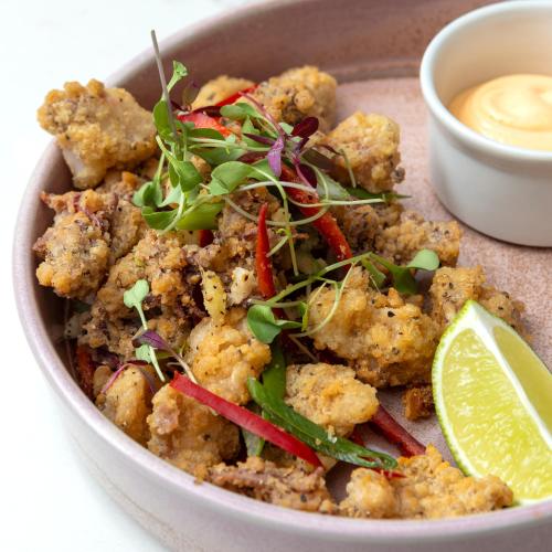 a bowl of food with a salad and a bowl of dipping sauce at Holiday Inn Manchester-Mediacityuk by IHG in Manchester