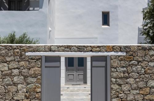 a white house with a stone wall and a door at Seven Suites in Glinado Naxos
