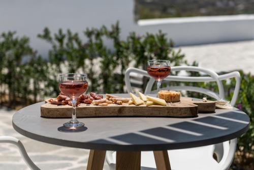 a table with two glasses of wine and food on it at Seven Suites in Glinado Naxos