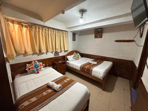クスコにあるHostal sambleño cusco Piero suiteのベッド2台とテレビがあるホテルの部屋