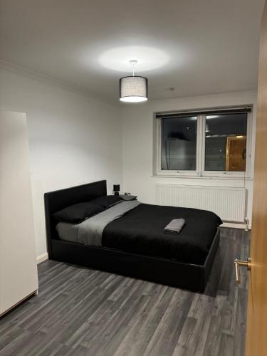 a bedroom with a black bed and a window at Spacious modern flat in Luton town centre in Luton