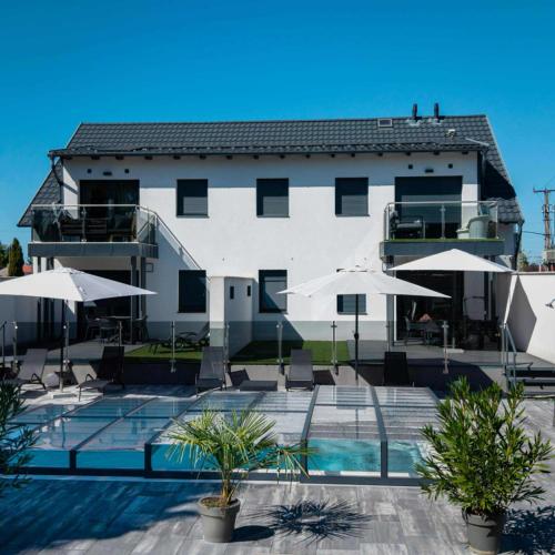 a large building with a swimming pool and umbrellas at Bala-Home Apartments & Pool in Balatonboglár