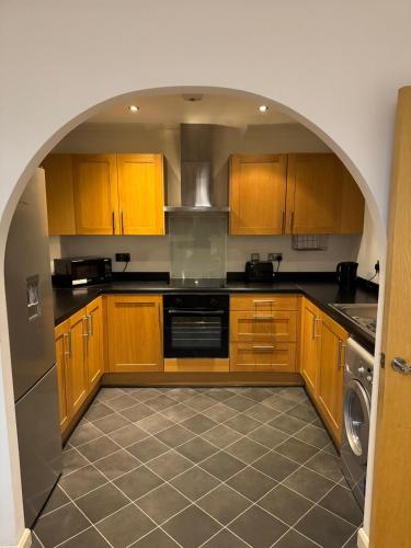 a kitchen with wooden cabinets and an archway in it at Spacious modern flat in Luton town centre in Luton