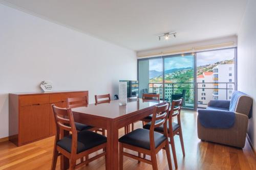 Un comedor con mesa y sillas y una gran ventana. en GuestReady - Modern space close to Formosa Beach, en Panasqueira