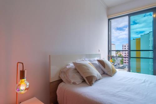 Un dormitorio con una cama blanca con una ventana grande. en GuestReady - Modern space close to Formosa Beach, en Panasqueira