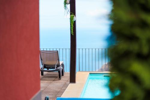 a chair sitting next to a swimming pool on a balcony at GuestReady - Exquisite stay with sea views in Arco da Calheta