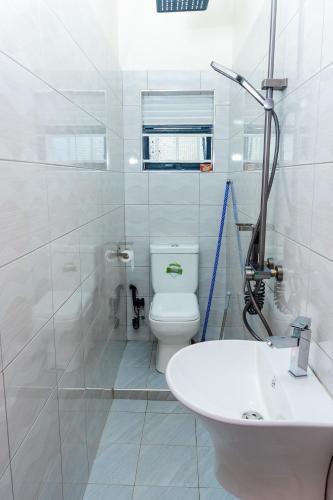 a white bathroom with a toilet and a sink at Bright & Airy 2BR Haven in Kampala