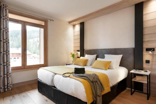 a bedroom with a large bed and a window at MGM Hôtels & Résidences - Résidence Le Hameau de l'Ours in Manigod