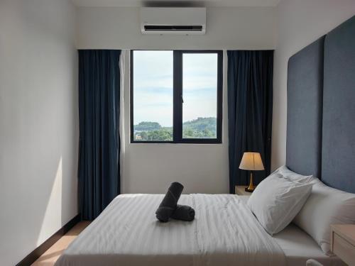 a black teddy bear sitting on a bed in a bedroom at Vetro11 Beside QEH1 by JUNE Homestay in Kota Kinabalu