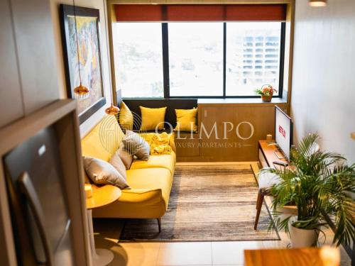 a living room with a yellow couch and windows at Suite Luxury en Puerto Santana in Guayaquil
