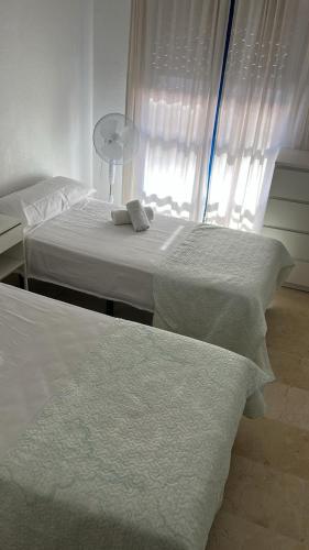 two beds with white sheets in a room with a window at Capitán - 2 habitaciones centro de Fuengirola in Fuengirola