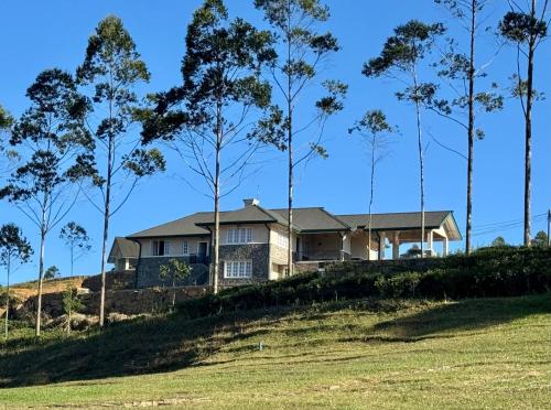 a house on a hill with trees in the foreground at The Mountain Links, Upcot, Nuwara Eliya in Maskeliya