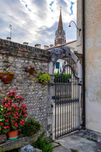 a gate to a stone wall with flowers and a church at Borgo Botol in Gaiarine