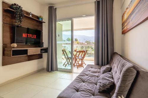 a living room with a couch and a television at 200m da praia com Piscina ,churrasqueira e Jacuzzi in Bertioga