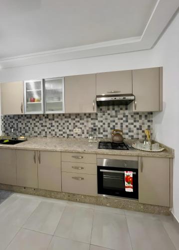 a kitchen with white cabinets and a stove top oven at Appartement luxueux - Piscines, Plage 300m, Résidence fermée in Martil