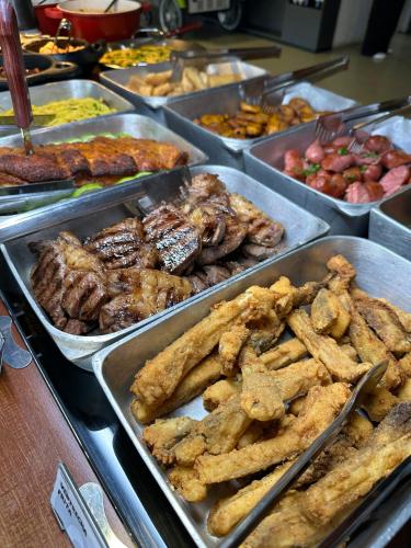 a buffet filled with different types of food in trays at Chapada Park Pousada e Restaurante in Chapada dos Guimarães