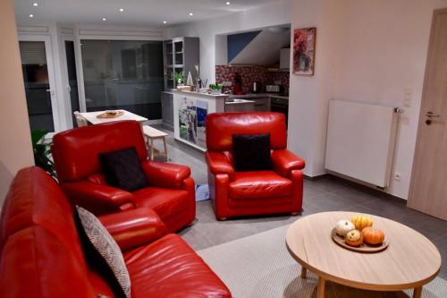 a living room with two red chairs and a table at l'Asperule in Rouvroy