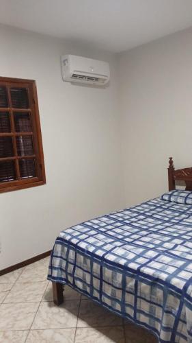 a bedroom with a bed with a blue and white blanket at Nosso cantinho in Saquarema