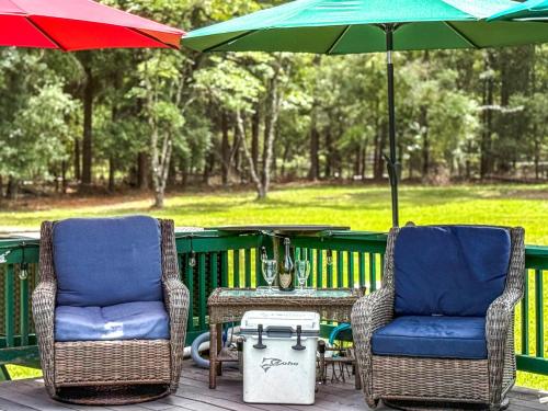 2 Stühle und ein Tisch mit Sonnenschirm in der Unterkunft Cabin Retreat on 8.5 Acres at High Springs, FL in High Springs