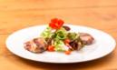 a white plate with a salad on a wooden table at Gasthof Adler in Tennenbronn