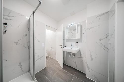 une salle de bain blanche avec un lavabo et une douche dans l'établissement The Vienna Fifteen - Boutique Hostel, à Vienne