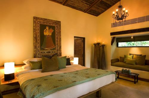 a bedroom with a bed and a chandelier at Baghvan Pench National Park - A Taj Safari Lodge in Behrai