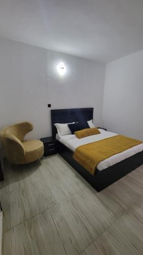 a bedroom with a large bed and a chair at Seven kings apartment Lekki in Araromi