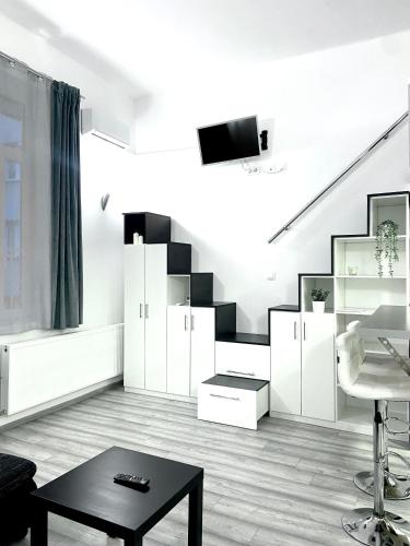 a living room with white furniture and a staircase at Belvárosi Apartman in Miskolc