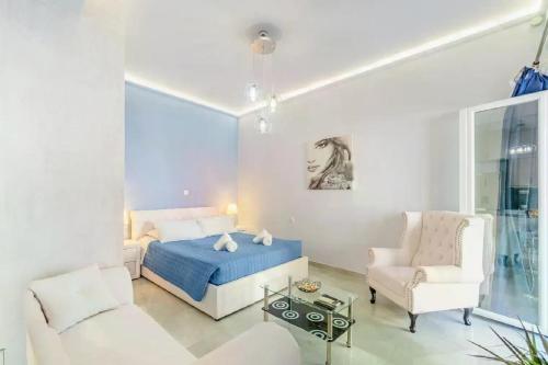 een witte slaapkamer met een bed en een stoel bij La casa di San Rocco in Corfu-stad