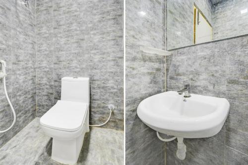 a bathroom with a white toilet and a sink at Hotel O Vijaya Grand in Pedda Ambarpet