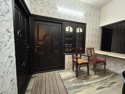 a room with a black door and two chairs and a table at Bluebell Homes in Kozhikode