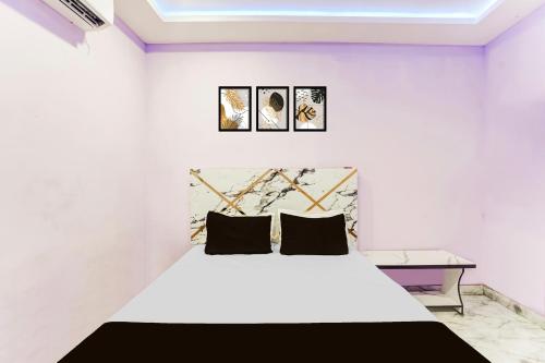 a bedroom with a white bed with two black pillows at Hotel O Yamuna Residency in Jamshedpur