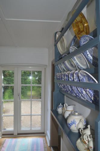 a shelf filled with blue and white dishes and a window at Cozy cottage getaway Holse in Brenderup