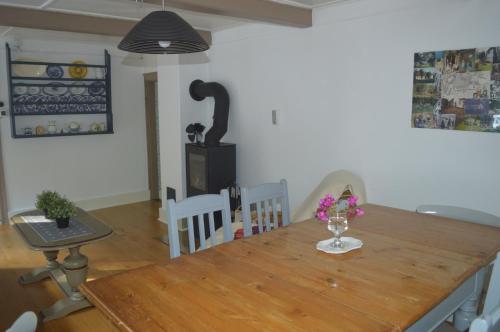 a dining room with a wooden table with flowers on it at Cozy cottage getaway Holse in Brenderup