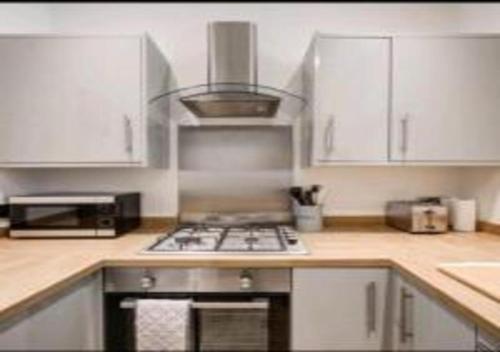 a kitchen with white cabinets and a stove top oven at 1BR Harbor Apartment , Family-Friendly , Sleeps 4 in Folkestone