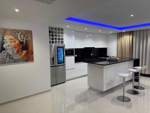 a kitchen with a bar with stools and a painting at Penthouse Ocean View in Mindelo
