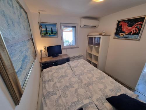 a small bedroom with a bed and a television at Luna's Seaview Residence - Ankaran in Ankaran