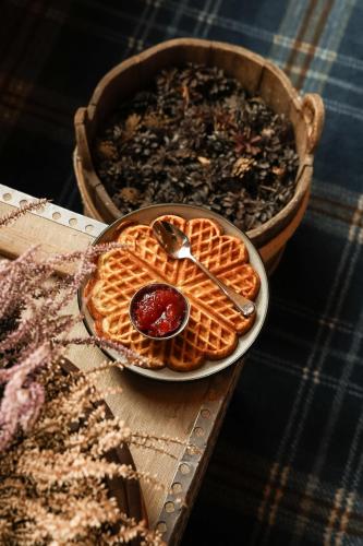 a plate of waffles on a table with a bowl of syrup at Pollfoss Boutique Hotel & Spa in Skjåk