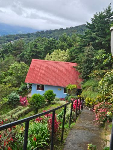 a small house with a red roof in a garden at Cabañas El Parador in Boquete