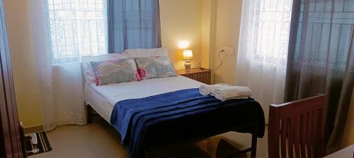 a small bed in a room with two windows at Godiva apartment in Cochin