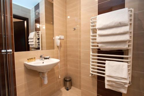 a bathroom with a sink and a mirror and towels at Hotel Klaudia in Juszczyn